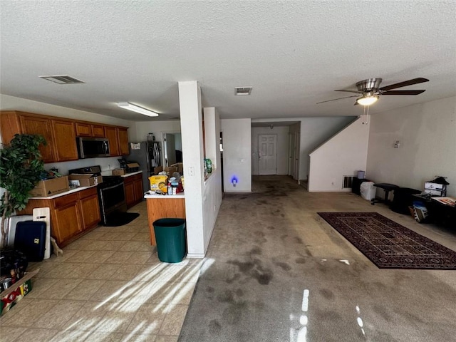 kitchen with black appliances, ceiling fan, a center island, and a textured ceiling