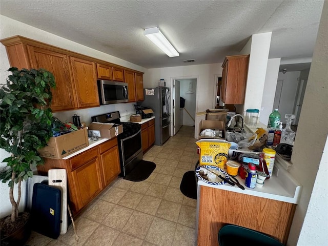 kitchen with a textured ceiling and appliances with stainless steel finishes