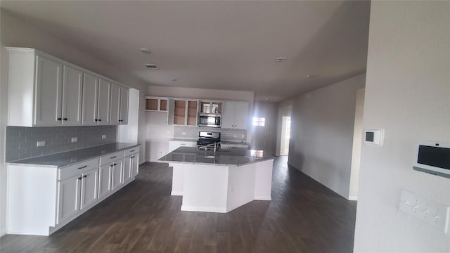 kitchen with white cabinets, stone countertops, a center island with sink, and appliances with stainless steel finishes