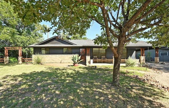 single story home featuring stone siding, a front lawn, and a sunroom