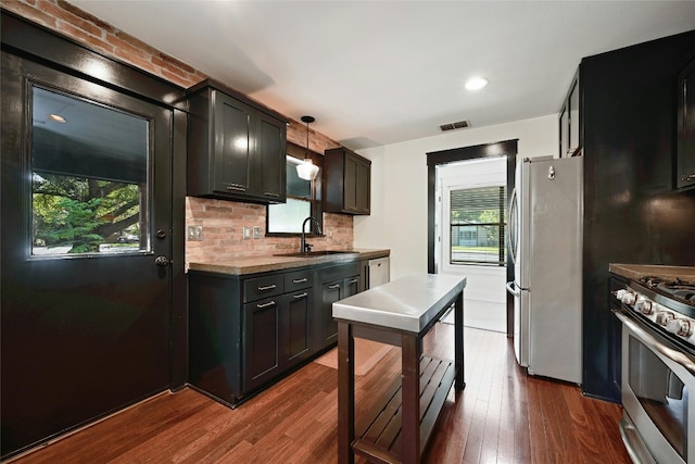 kitchen featuring visible vents, a sink, backsplash, appliances with stainless steel finishes, and dark wood-style flooring