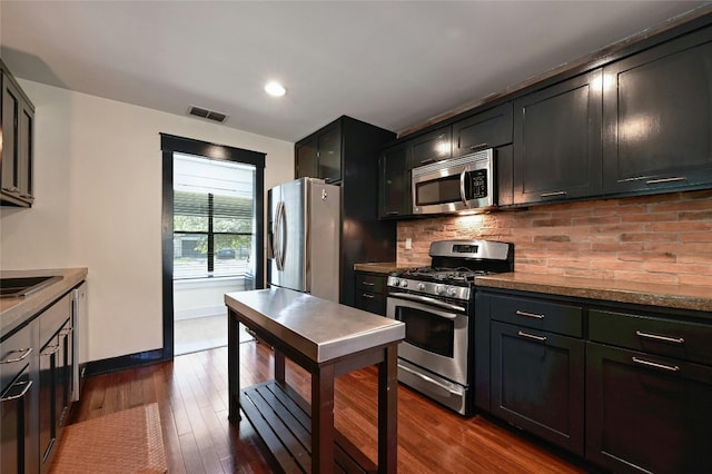 kitchen with visible vents, backsplash, appliances with stainless steel finishes, baseboards, and dark wood-style flooring