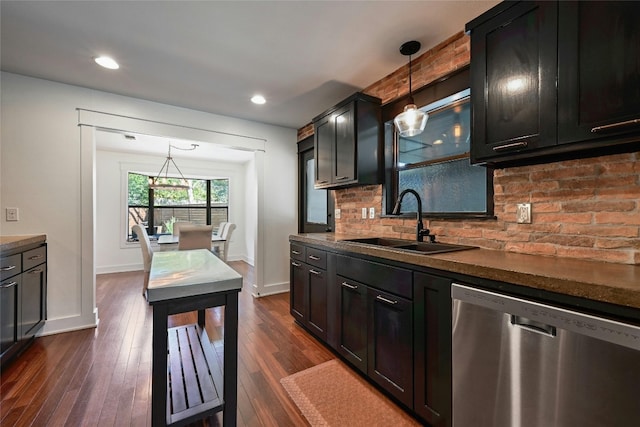 kitchen with dark wood finished floors, a sink, dishwasher, dark countertops, and backsplash