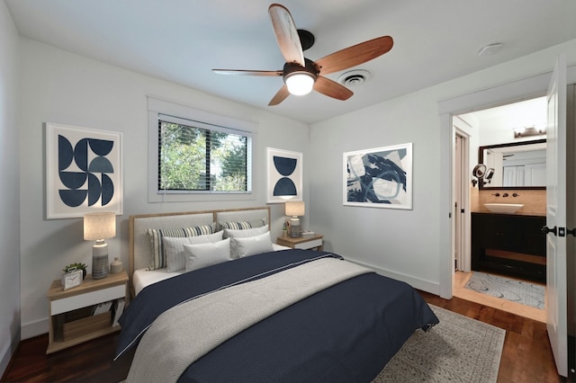 bedroom with baseboards, dark wood-style floors, visible vents, and connected bathroom