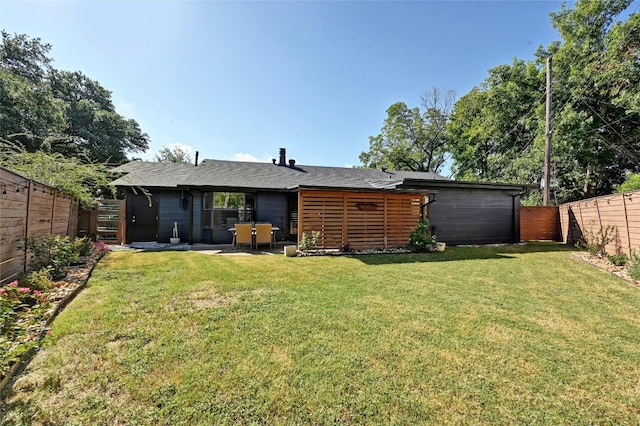 rear view of house with a yard, a fenced backyard, and a patio area