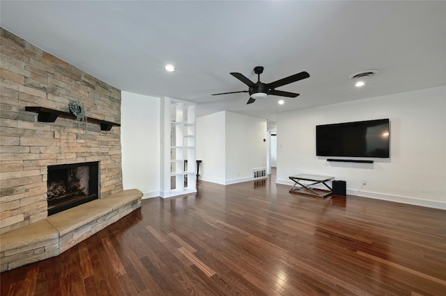 unfurnished living room with visible vents, baseboards, a stone fireplace, and wood finished floors