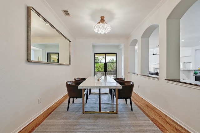 dining space with crown molding, a notable chandelier, and hardwood / wood-style flooring