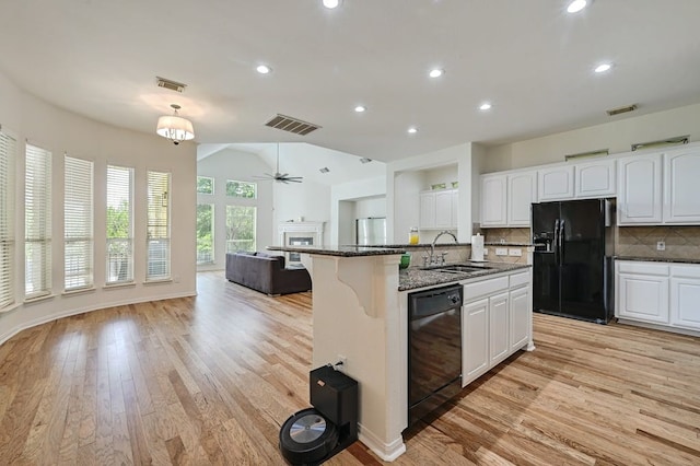 kitchen featuring tasteful backsplash, sink, black appliances, dark stone countertops, and white cabinetry