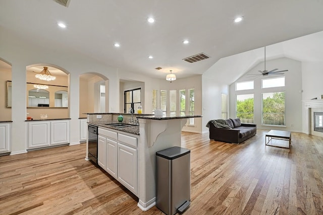 kitchen featuring sink, a tile fireplace, a center island with sink, light hardwood / wood-style flooring, and white cabinetry