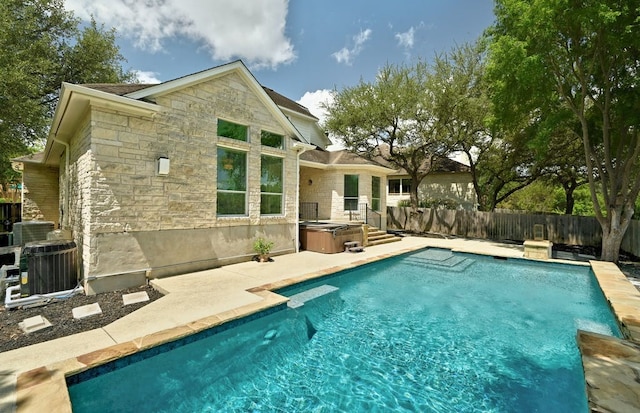 rear view of house featuring a swimming pool with hot tub, a patio, and central AC unit