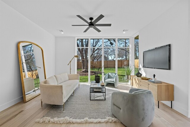 living room with light wood-type flooring, expansive windows, and ceiling fan