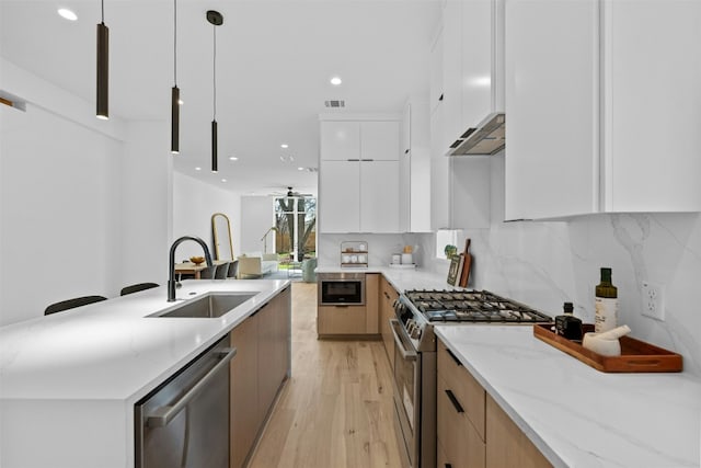 kitchen featuring light stone countertops, white cabinetry, sink, hanging light fixtures, and stainless steel appliances