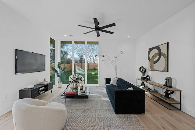 living room with ceiling fan, a wall of windows, and light hardwood / wood-style flooring