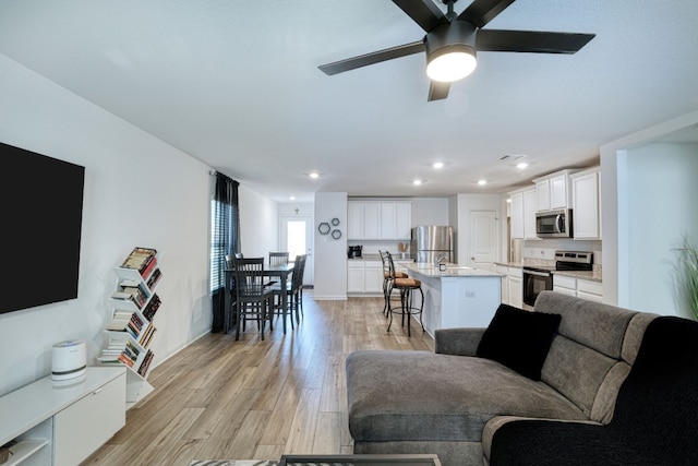 living room featuring ceiling fan, sink, and light hardwood / wood-style flooring