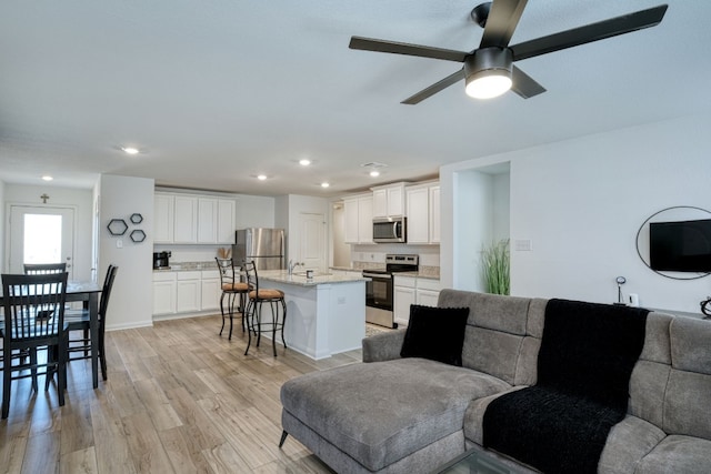 living room featuring ceiling fan, sink, and light hardwood / wood-style floors