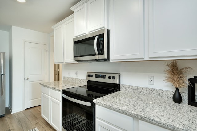 kitchen featuring light hardwood / wood-style floors, light stone countertops, white cabinetry, and stainless steel appliances