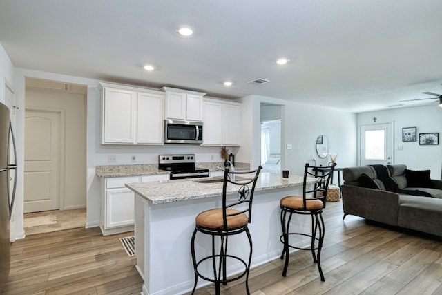 kitchen featuring an island with sink, white cabinets, and stainless steel appliances