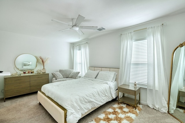 carpeted bedroom featuring multiple windows and ceiling fan