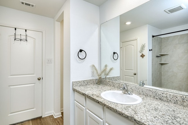 bathroom featuring tiled shower, vanity, and hardwood / wood-style flooring