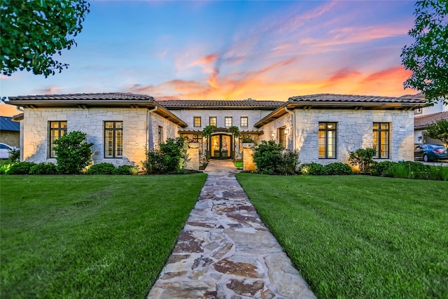 mediterranean / spanish house featuring a yard and french doors