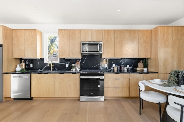 kitchen featuring stainless steel appliances, light wood-type flooring, light brown cabinets, and backsplash