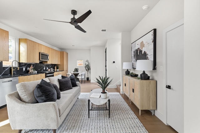 living room featuring ceiling fan, sink, and light wood-type flooring