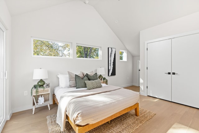 bedroom featuring vaulted ceiling, light wood-type flooring, and a closet