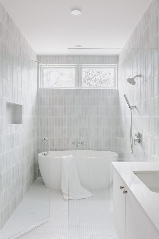 bathroom with tile patterned floors, vanity, independent shower and bath, and tile walls