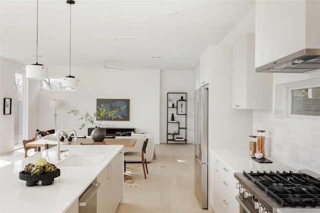 kitchen with white cabinetry, sink, wall chimney exhaust hood, stainless steel appliances, and pendant lighting