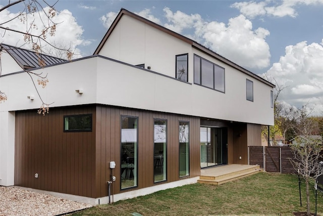 back of property featuring a deck and a lawn