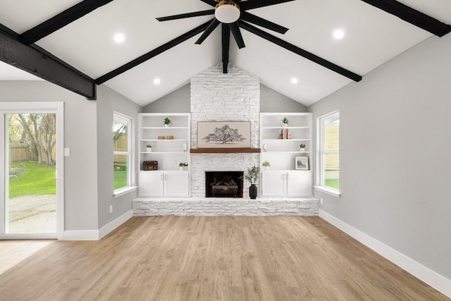 unfurnished living room with built in shelves, a fireplace, lofted ceiling with beams, and light wood-type flooring