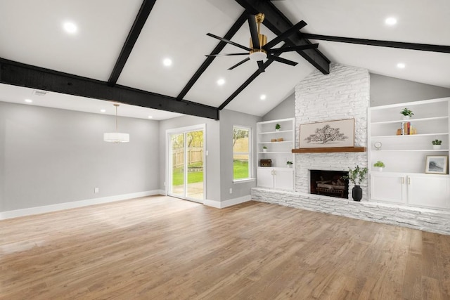 unfurnished living room with ceiling fan, built in features, lofted ceiling with beams, a fireplace, and light wood-type flooring