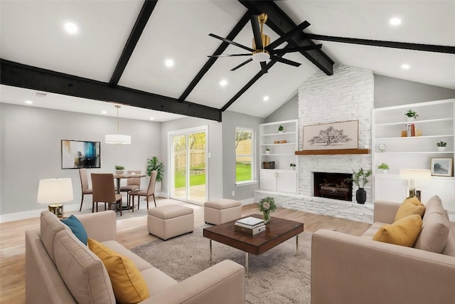 living room with high vaulted ceiling, a stone fireplace, light hardwood / wood-style flooring, ceiling fan, and beam ceiling