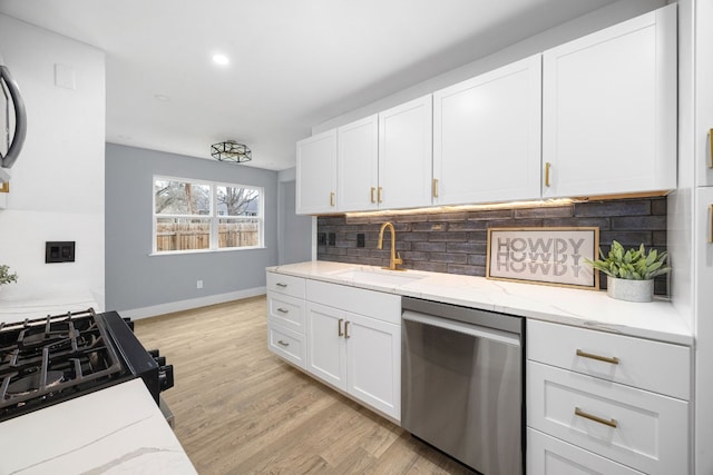 kitchen with decorative backsplash, white cabinets, dishwasher, light stone countertops, and a sink