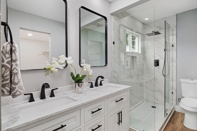 full bath featuring double vanity, wood finished floors, a sink, and toilet