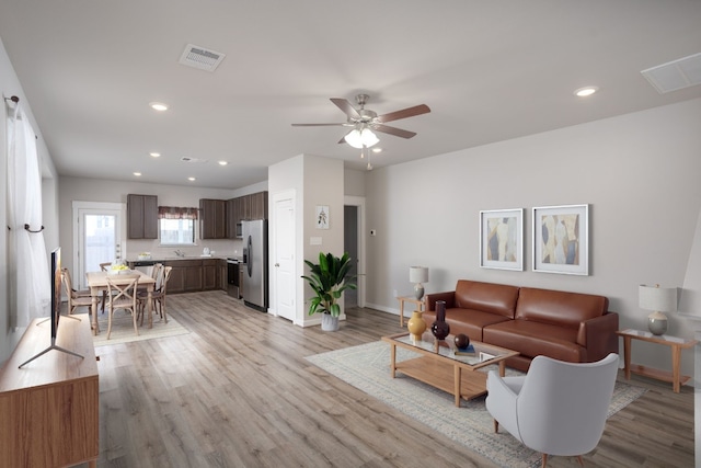 living room featuring ceiling fan, sink, and light hardwood / wood-style flooring