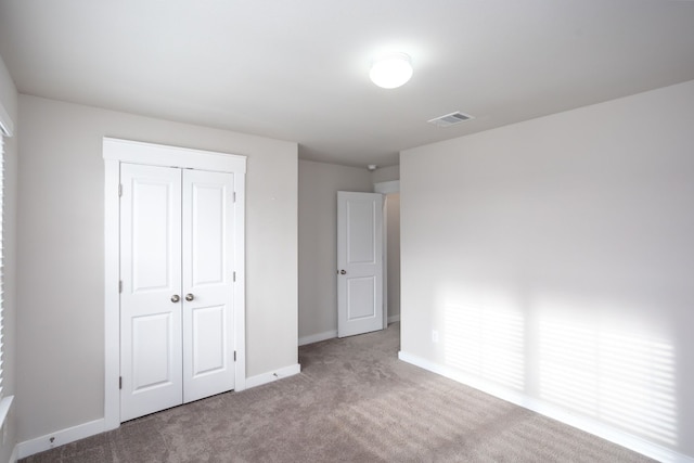 unfurnished bedroom featuring light carpet and a closet