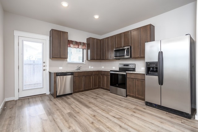 kitchen with sink, dark brown cabinetry, stainless steel appliances, and light wood-type flooring