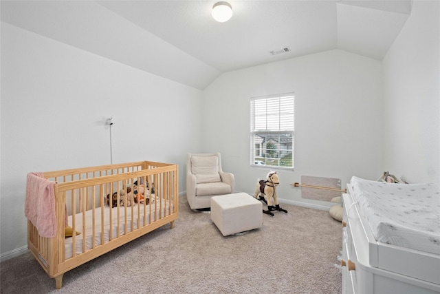 bedroom featuring lofted ceiling, a crib, and carpet floors