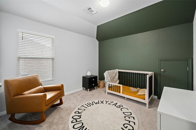 bedroom with a crib, carpet, and lofted ceiling