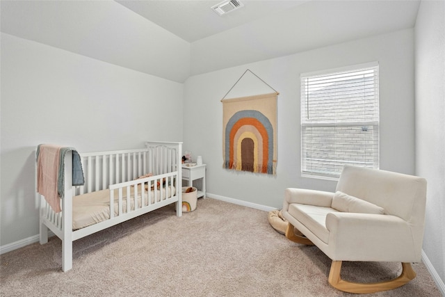 carpeted bedroom with a crib and lofted ceiling