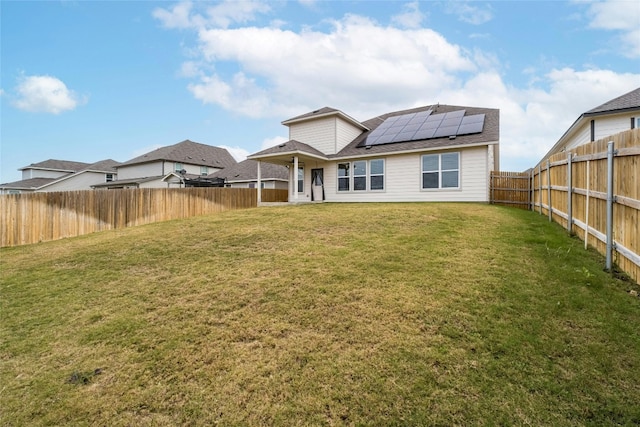 rear view of house with a yard and solar panels