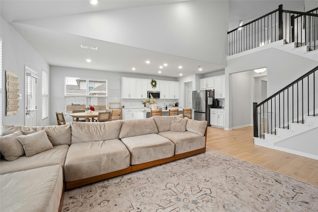 living room with high vaulted ceiling and light wood-type flooring