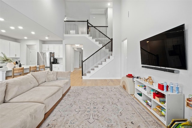 living room with a towering ceiling and light wood-type flooring