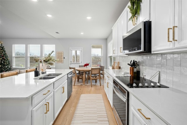 kitchen featuring sink, tasteful backsplash, a center island with sink, white cabinets, and appliances with stainless steel finishes