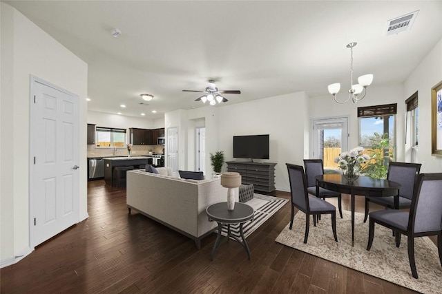 living room with dark hardwood / wood-style flooring and ceiling fan with notable chandelier