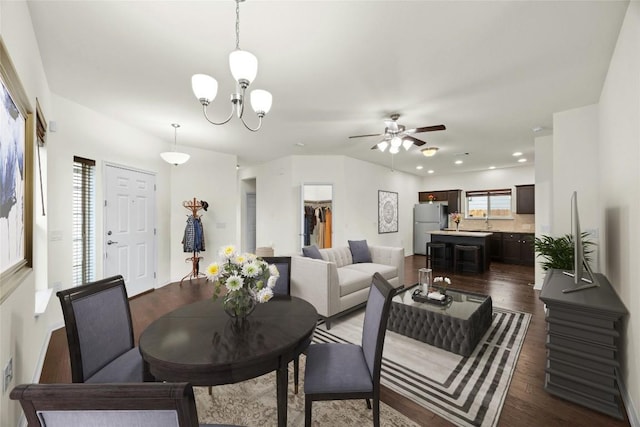 dining room with ceiling fan with notable chandelier and dark hardwood / wood-style floors