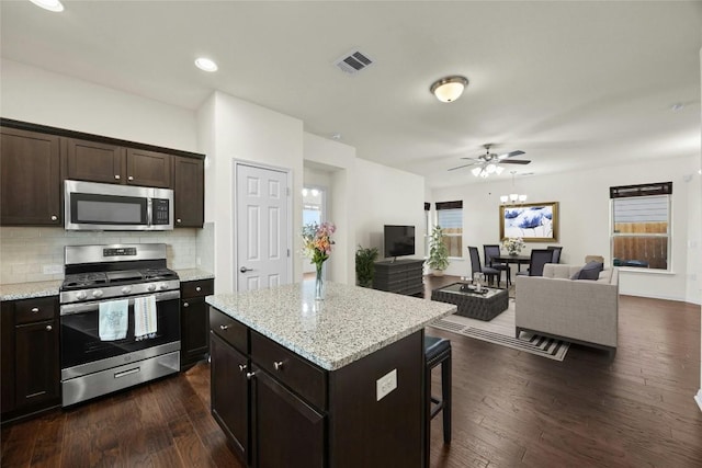 kitchen featuring decorative backsplash, a center island, stainless steel appliances, and dark brown cabinets