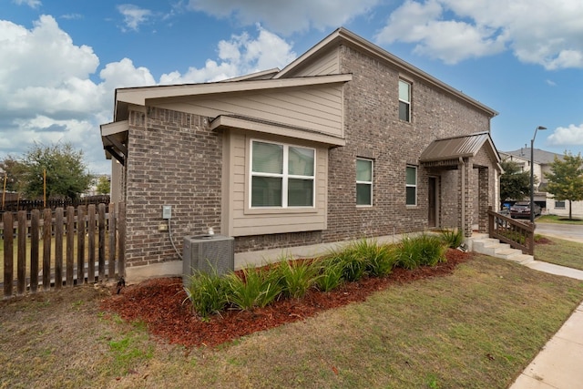 view of side of property with a yard and central AC