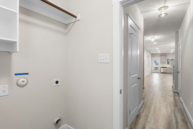 clothes washing area with light hardwood / wood-style flooring, gas dryer hookup, and electric dryer hookup